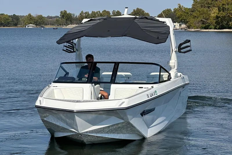 Slide: The Image of 2024 Nautique G23 Coastal Edition boat cruising on a serene lake. - 16