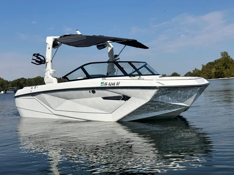 Slide: The Image of 2024 Nautique G23 Coastal Edition boat on calm water, featuring sleek design and canopy. - 2
