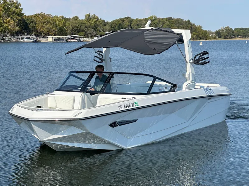 Slide: The Image of 2024 Nautique G23 Coastal Edition boat cruising on a serene lake. - 3