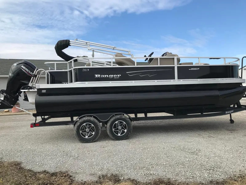 Slide: The Image of 2025 Ranger Reata 200F pontoon boat on trailer, parked outdoors. - 2