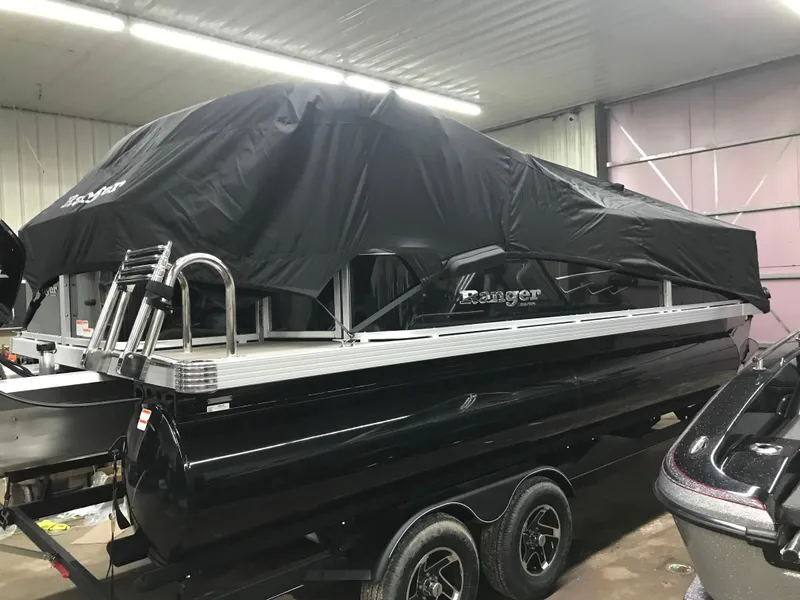 Slide: The Image of 2025 Ranger Reata 200F pontoon boat with black cover in a garage setting. - 35