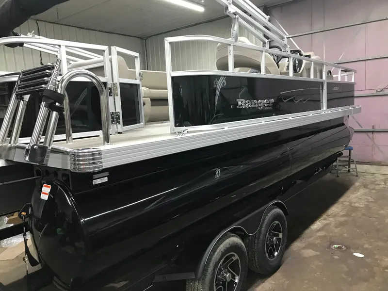 Slide: The Image of 2025 Ranger Reata 200F pontoon boat with Mercury outboard motor in a garage. - 4