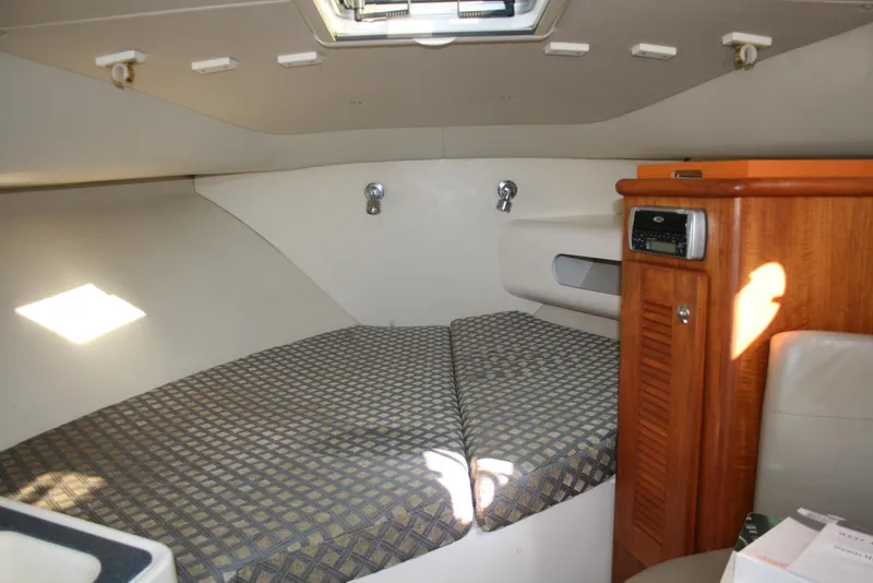 Slide: The Image of 2005 Pursuit 3370 Offshore cabin interior with bed and wooden storage. - 10