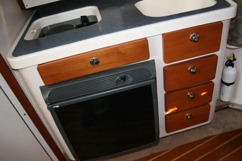 Slide: The Image of 2005 Pursuit 3370 Offshore boat kitchen with sink, stove, and wooden cabinets. - 12