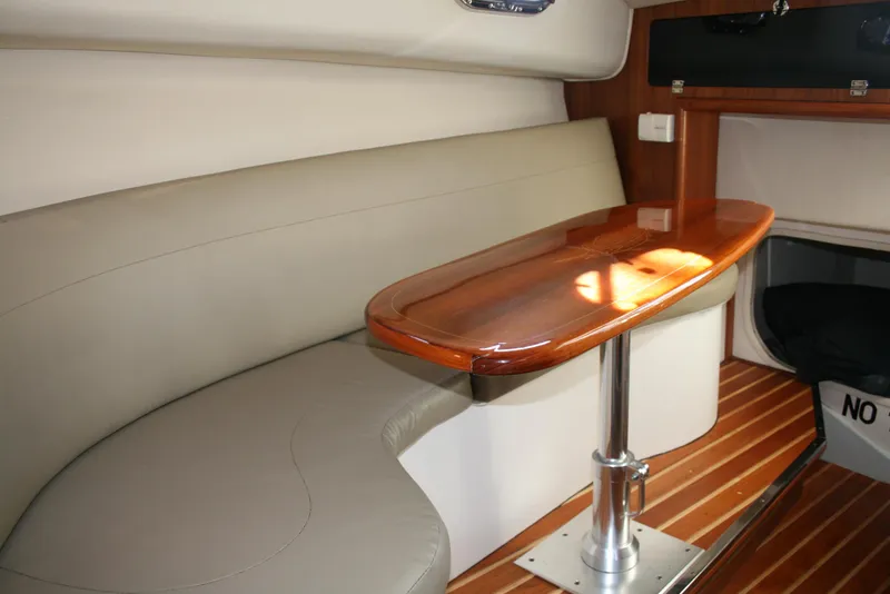 Slide: The Image of Interior of 2005 Pursuit 3370 Offshore boat with wooden table and cushioned seating. - 13