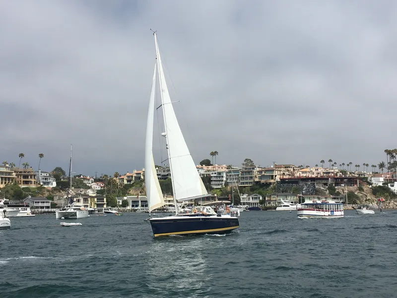 Slide: The Image of 2014 Marlow Hunter 40 sailboat cruising near coastal homes and other boats. - 4