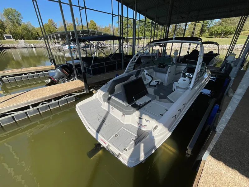 Slide: The Image of 2024 Chaparral 23 SSi boat docked in a marina under a covered slip. - 12