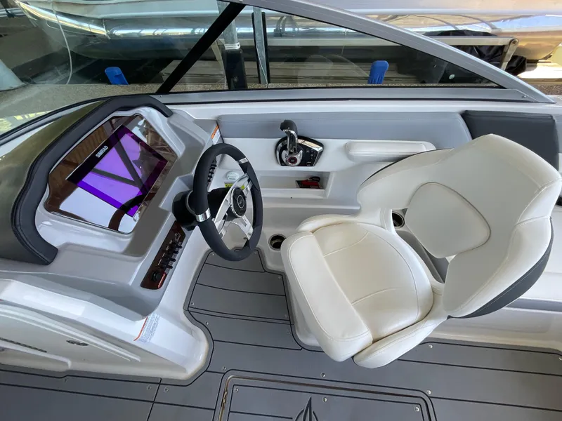 Slide: The Image of 2024 Chaparral 23 SSi boat cockpit with steering wheel and white captain's chair. - 14