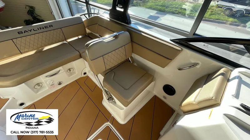 Slide: The Image of 2025 Bayliner D22I boat interior with tan seating and Marine Center contact information. - 14