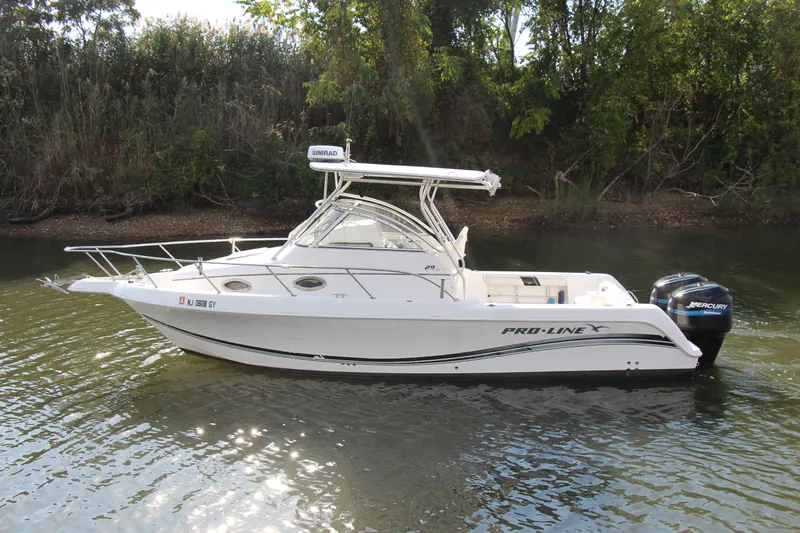 Slide: The Image of 2005 Pro-Line 29 Express boat on calm water, surrounded by lush greenery. - 14