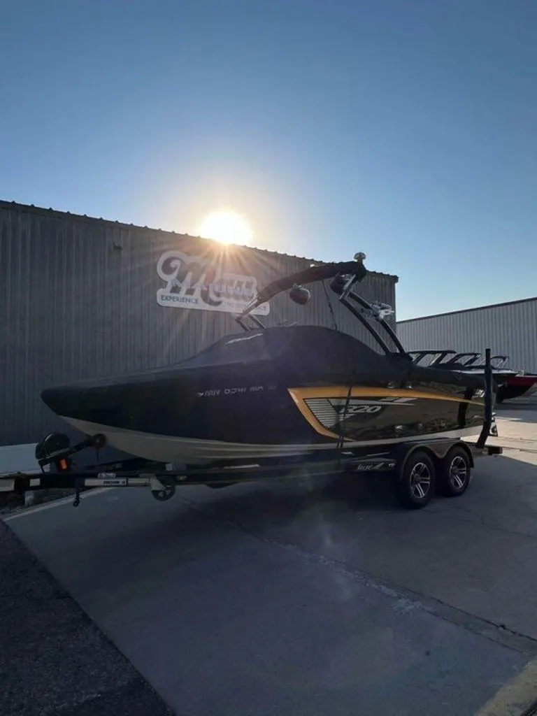 Slide: The Image of 2015 Tigé R20 boat on trailer, parked outside a building with sun in the background. - 0