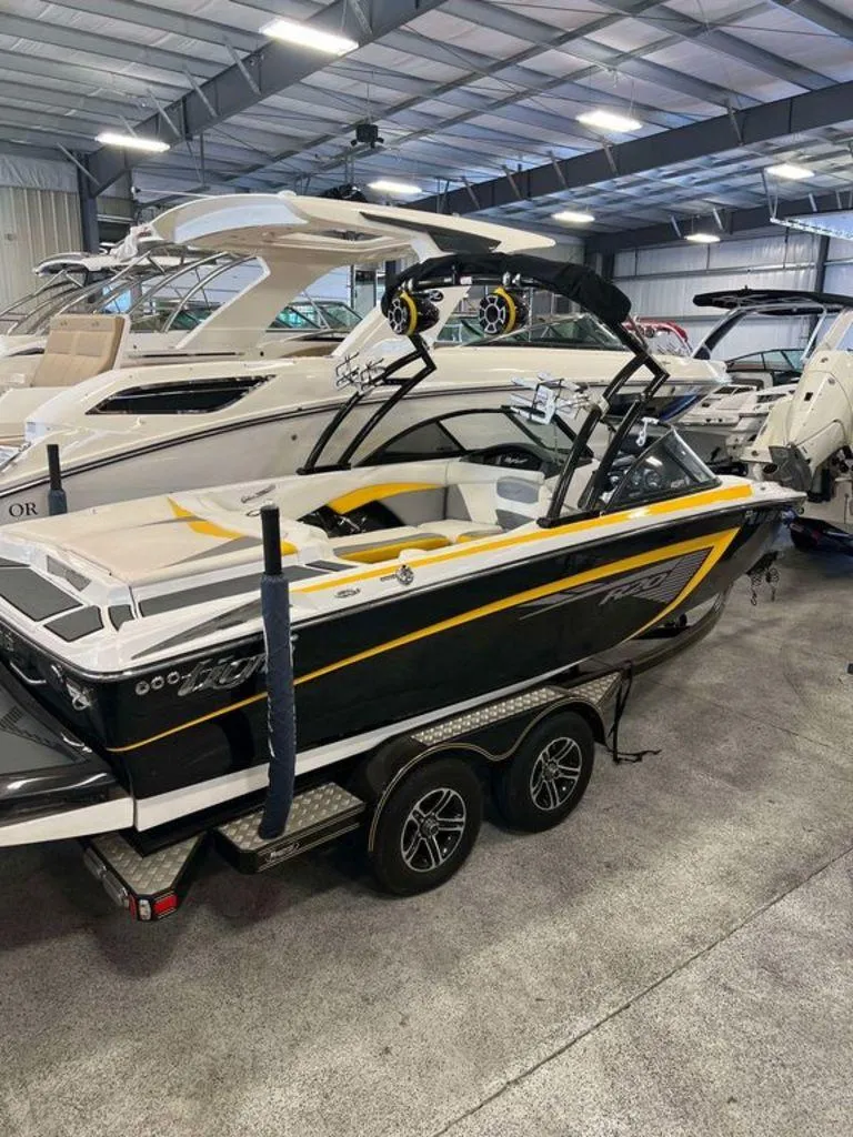 Slide: The Image of 2015 Tigé R20 boat in showroom, black and yellow design, on trailer. - 1