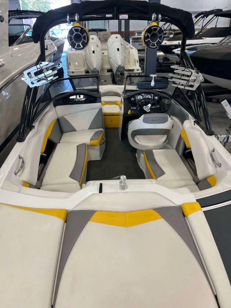 Slide: The Image of 2015 Tigé R20 boat interior with yellow and gray seating, speakers, and steering console. - 2