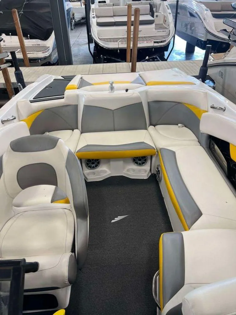 Slide: The Image of 2015 Tigé R20 boat interior with white, gray, and yellow seating in a showroom. - 5