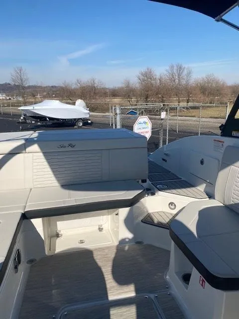 Slide: The Image of 2025 Sea Ray SPX 230 boat interior with seating, docked outdoors under clear blue sky. - 13