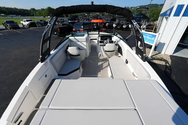 Slide: The Image of 2025 Sea Ray SPX 230 boat interior with seating and helm, parked outdoors. - 26