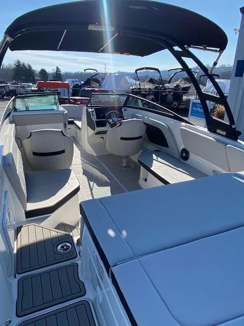 Slide: The Image of 2025 Sea Ray SPX 230 boat interior with seating and helm, under a sunny sky. - 9