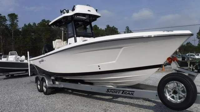 Slide: The Image of 2023 Blue Wave 2800 Makaira boat on trailer, parked on gravel lot. - 2