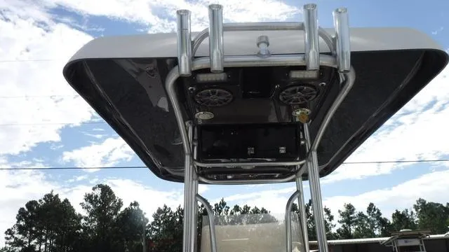 Slide: The Image of 2013 ShearWater 25 Bay boat T-top with rod holders and speakers against a cloudy sky. - 7
