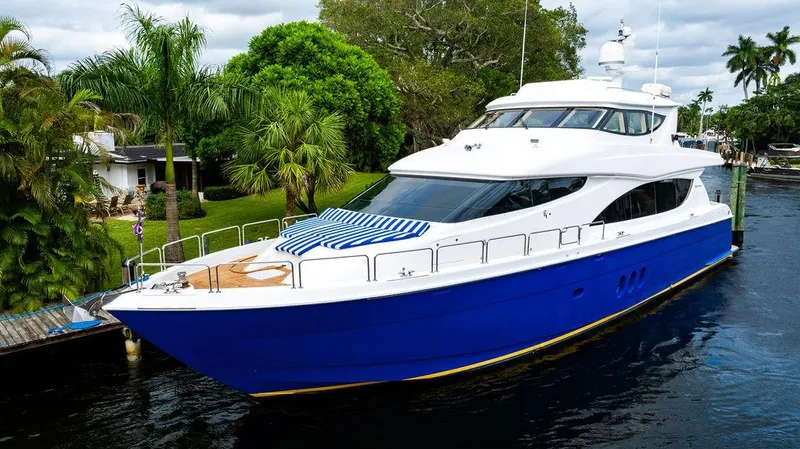 Slide: The Image of 2007 Hatteras Enclosed Flybridge yacht with blue hull docked by lush greenery. - 3