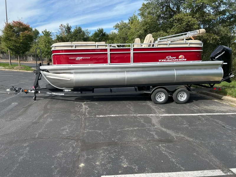 The Image of 2025 Sun Tracker Party Barge 22 XP3 pontoon boat on trailer in parking lot. - 0
