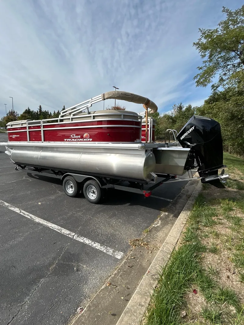 Slide: The Image of 2025 Sun Tracker Party Barge 22 XP3 pontoon boat on trailer in parking lot. - 2