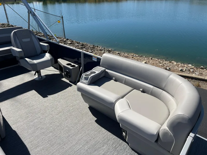 Slide: The Image of 2025 Godfrey Xperience 2286 SFL pontoon boat interior with gray seating by a lake. - 10