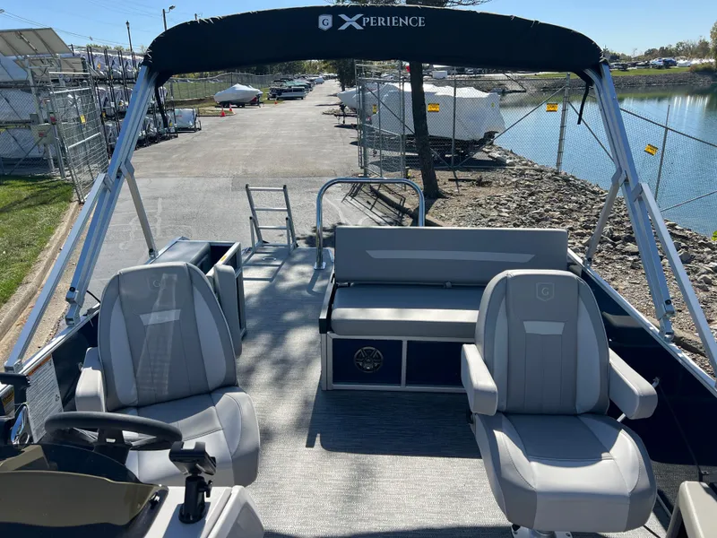 Slide: The Image of 2025 Godfrey Xperience 2286 SFL pontoon boat with seating, docked by a calm waterfront. - 12