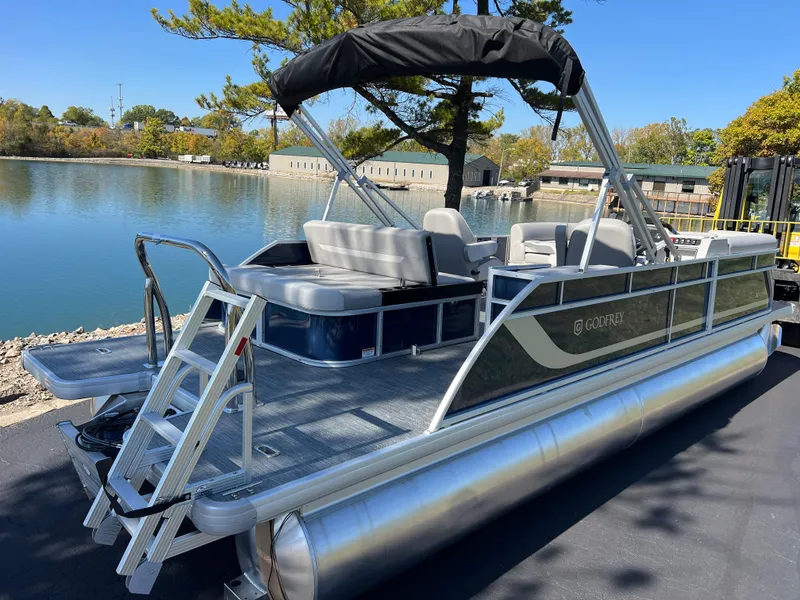 Slide: The Image of 2025 Godfrey Xperience 2286 SFL pontoon boat docked by a serene lake. - 2