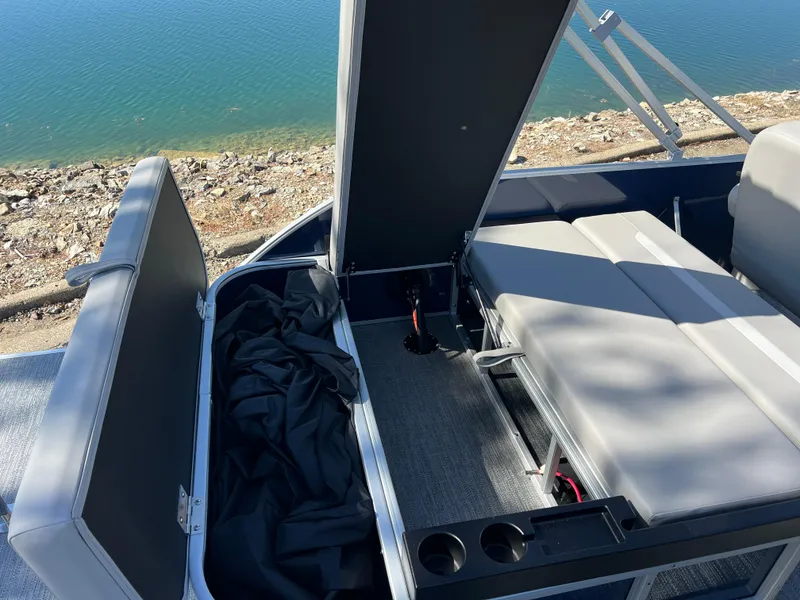 Slide: The Image of 2025 Godfrey Xperience 2286 SFL boat interior with seating and storage, near water. - 20