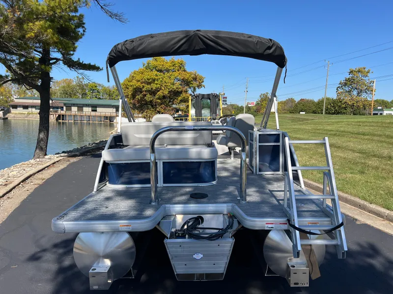 Slide: The Image of 2025 Godfrey Xperience 2286 SFL pontoon boat, docked near a scenic lakeside area. - 3