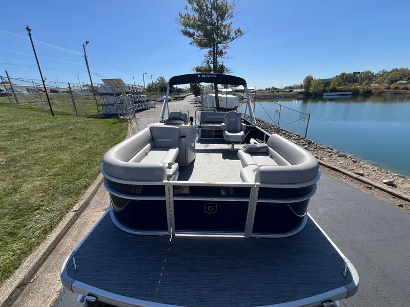 Slide: The Image of 2025 Godfrey Xperience 2286 SFL pontoon boat docked by a serene lakeside. - 6