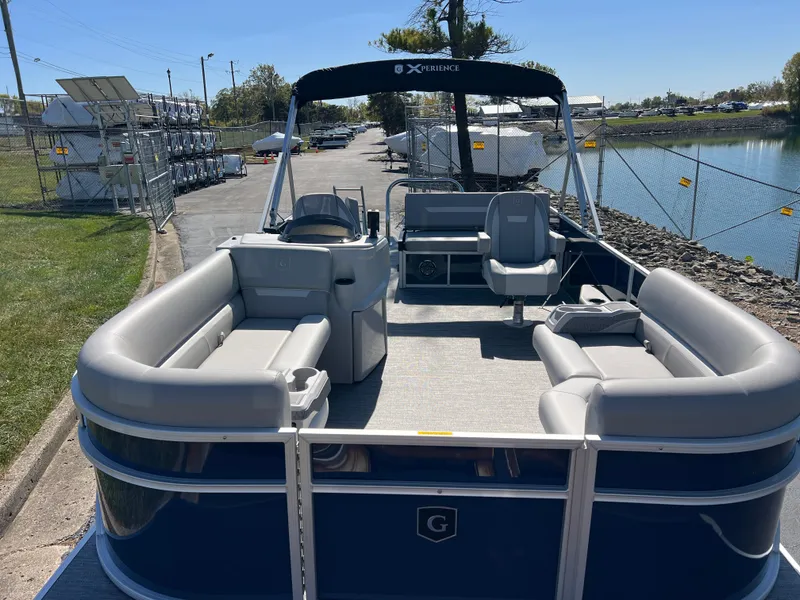 Slide: The Image of 2025 Godfrey Xperience 2286 SFL pontoon boat with spacious seating, docked by a lakeside. - 7