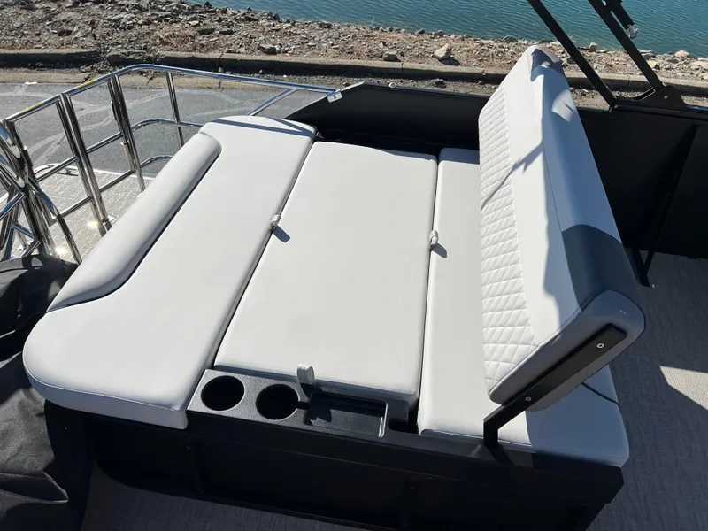 Slide: The Image of 2025 Godfrey SWEETWATER 2286 SFL boat seating with cup holders, near water. - 18