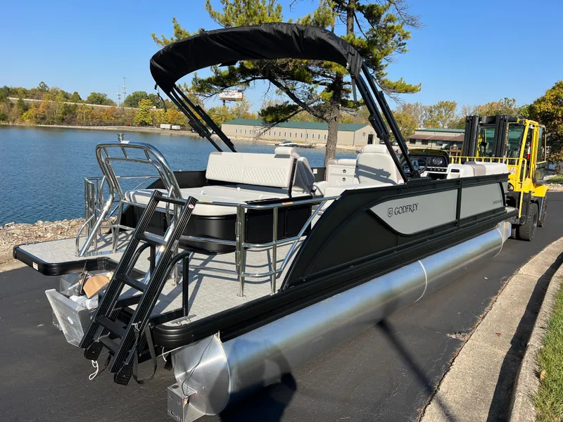 Slide: The Image of 2025 Godfrey SWEETWATER 2286 SFL pontoon boat by a lake, featuring sleek design. - 2