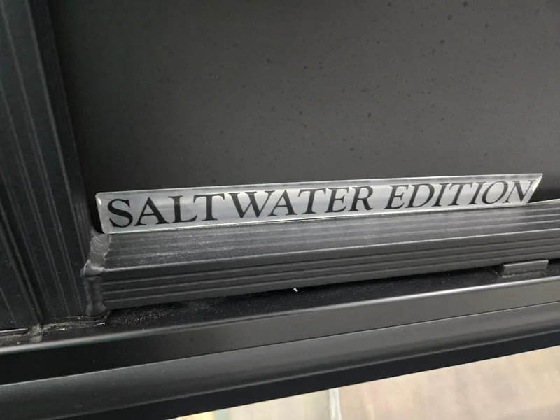 Slide: The Image of 2024 Harris Cruiser 230 Saltwater Edition nameplate on a sleek black surface. - 29