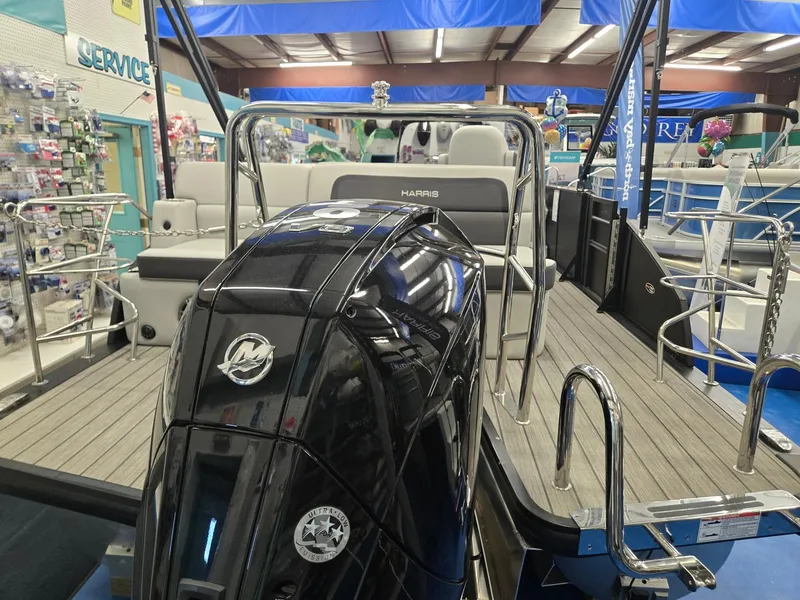 Slide: The Image of 2024 Harris Cruiser 230 pontoon boat with sleek black motor in showroom. - 5