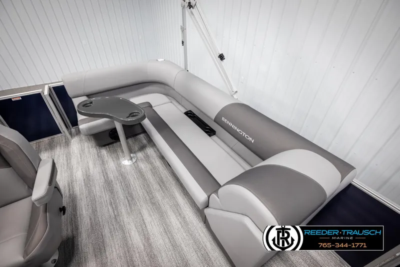 Slide: The Image of 2025 Bennington 188 SSSE boat interior with gray seating and table, showcased by Reeder-Trausch Marine. - 23