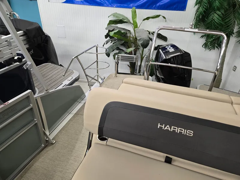 Slide: The Image of 2025 Harris Cruiser 210 boat interior with seating and motor, displayed indoors. - 12