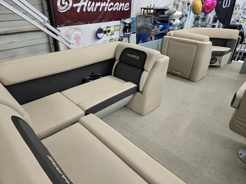 Slide: The Image of 2025 Harris Cruiser 210 boat interior with beige seating in a showroom. - 18