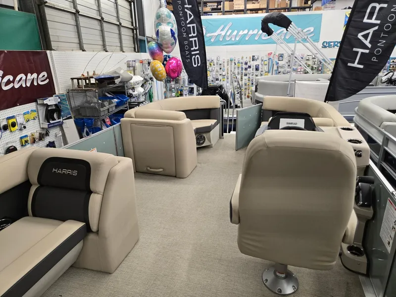 Slide: The Image of 2025 Harris Cruiser 210 pontoon boat interior with beige seating in showroom. - 19