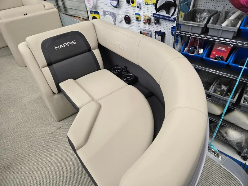 Slide: The Image of 2025 Harris Cruiser 210 boat seating with beige upholstery and cup holders in a showroom. - 4