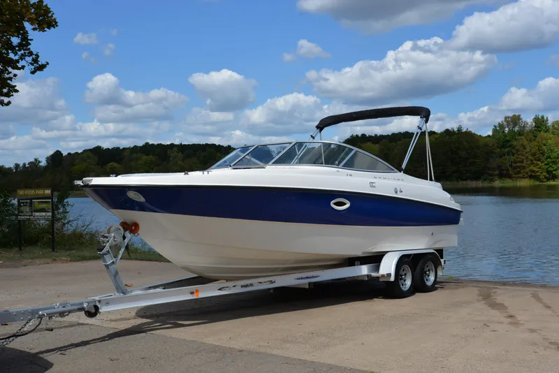 Slide: The Image of 2006 Bayliner 249 SD boat on trailer by a lake under blue sky. - 10