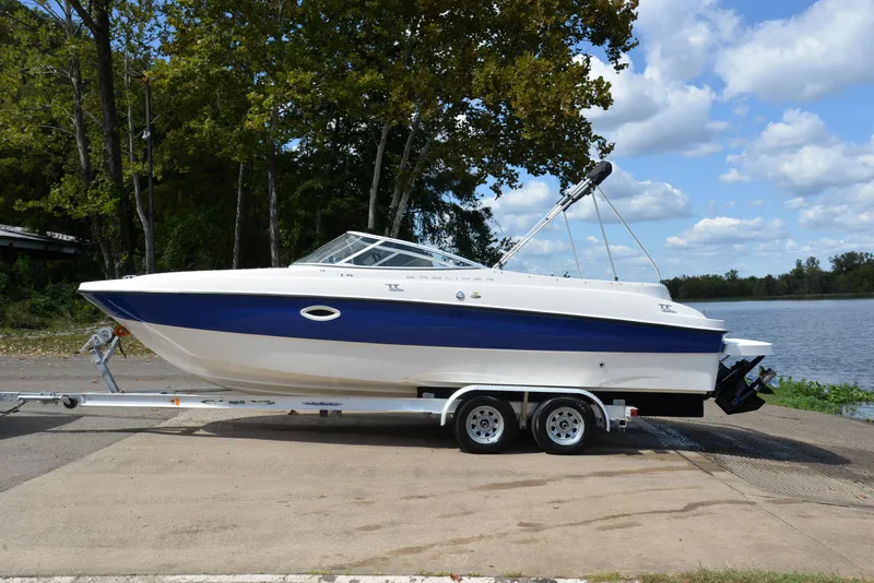 Slide: The Image of 2006 Bayliner 249 SD boat on trailer by a lake, under a clear sky. - 11