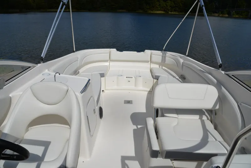Slide: The Image of 2006 Bayliner 249 SD boat interior with white seating and open deck on calm water. - 20