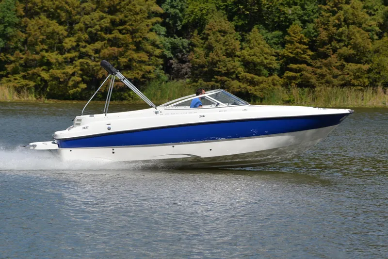 Slide: The Image of 2006 Bayliner 249 SD speedboat cruising on a lake with lush green trees. - 3