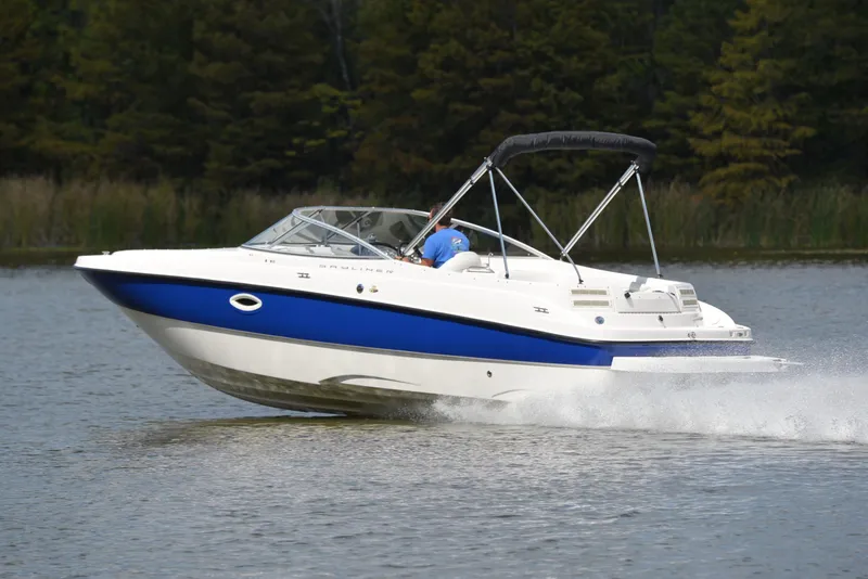 Slide: The Image of 2006 Bayliner 249 SD boat cruising on a lake with lush greenery in the background. - 4