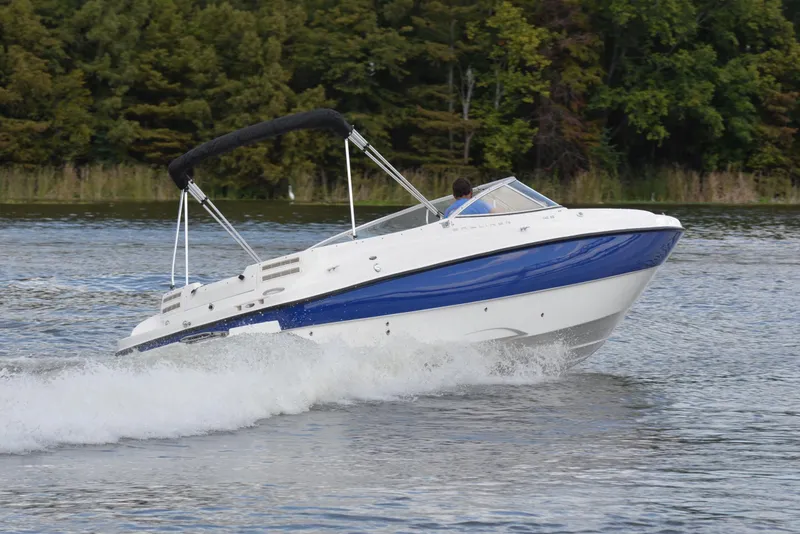 Slide: The Image of 2006 Bayliner 249 SD boat cruising on a lake with lush green trees. - 5