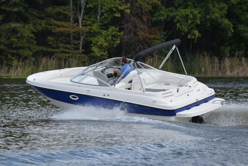 Slide: The Image of 2006 Bayliner 249 SD boat cruising on a lake with lush green trees. - 6