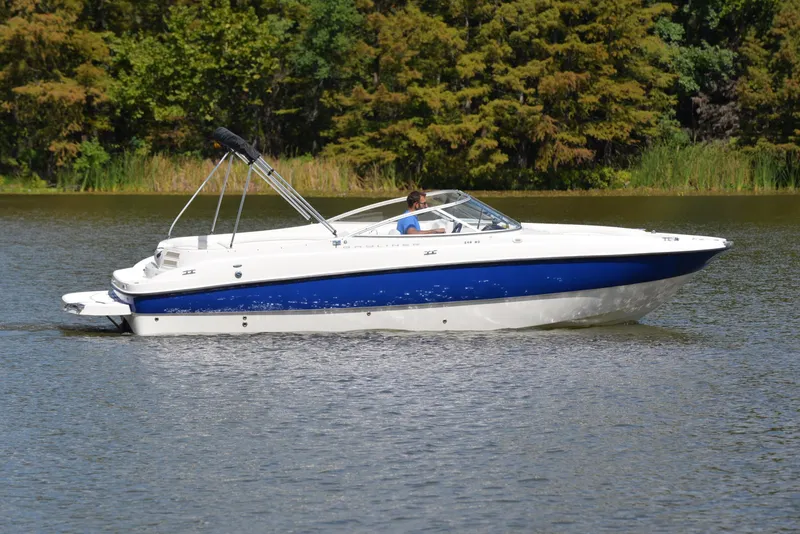 Slide: The Image of 2006 Bayliner 249 SD boat cruising on a calm lake with forested background. - 7